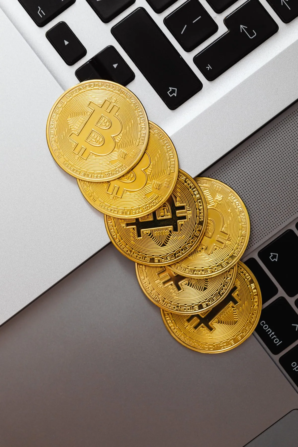 Bitcoin coins resting on a laptop keyboard next to a price chart