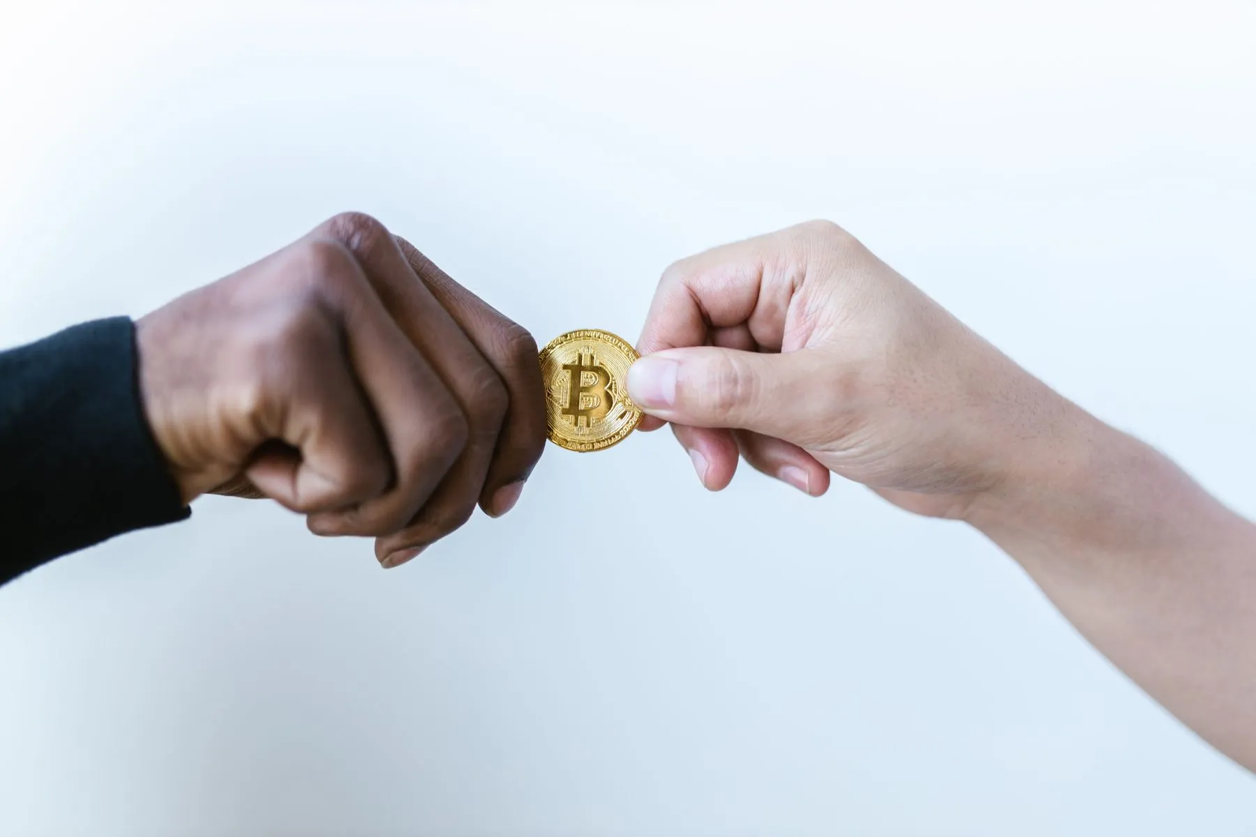 Two hands passing a crypto coin, illustrating buying and sending XRP in Georgia