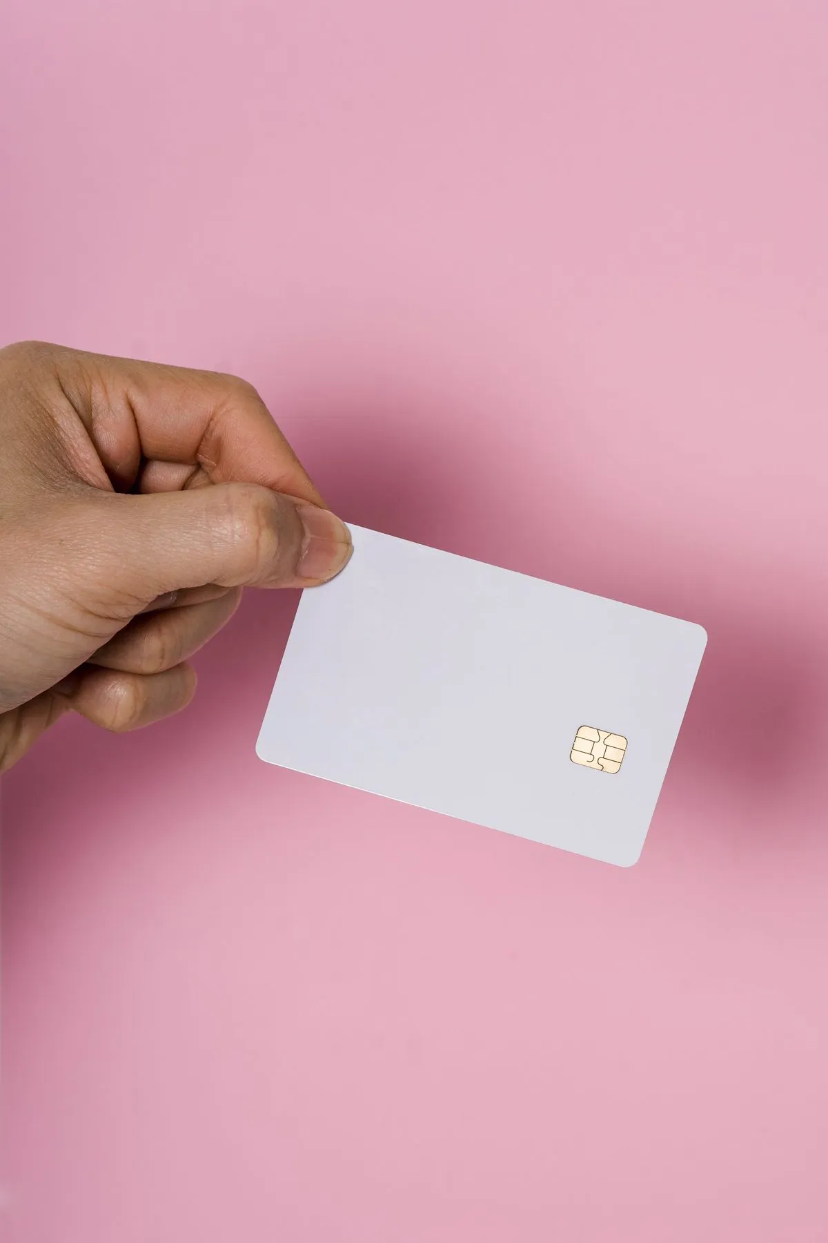 Hand holding a blank white card on a pink background