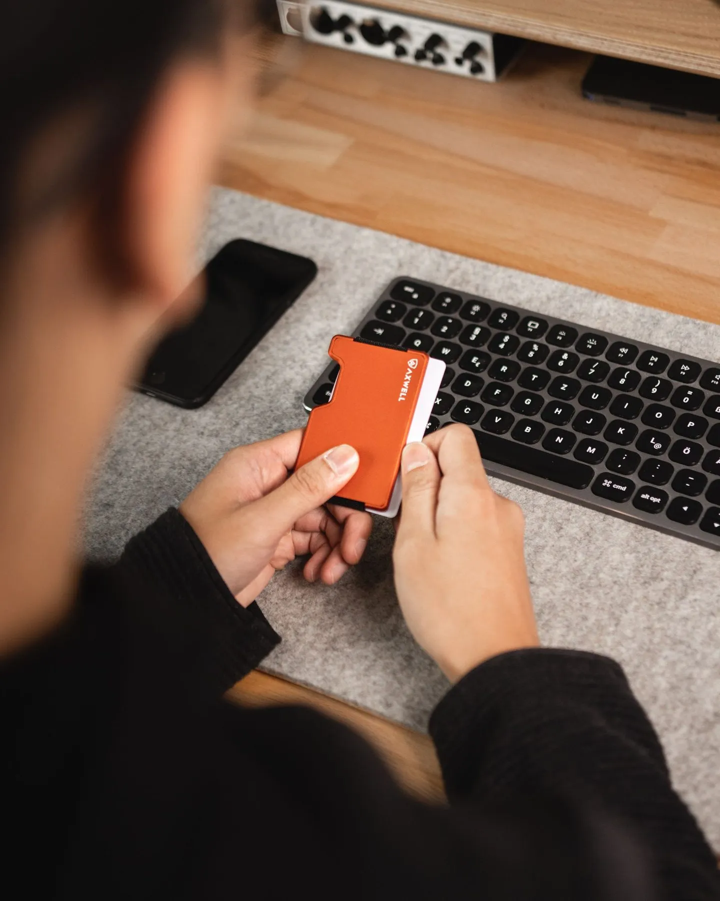 Person holding a card-style crypto hardware wallet at a desk