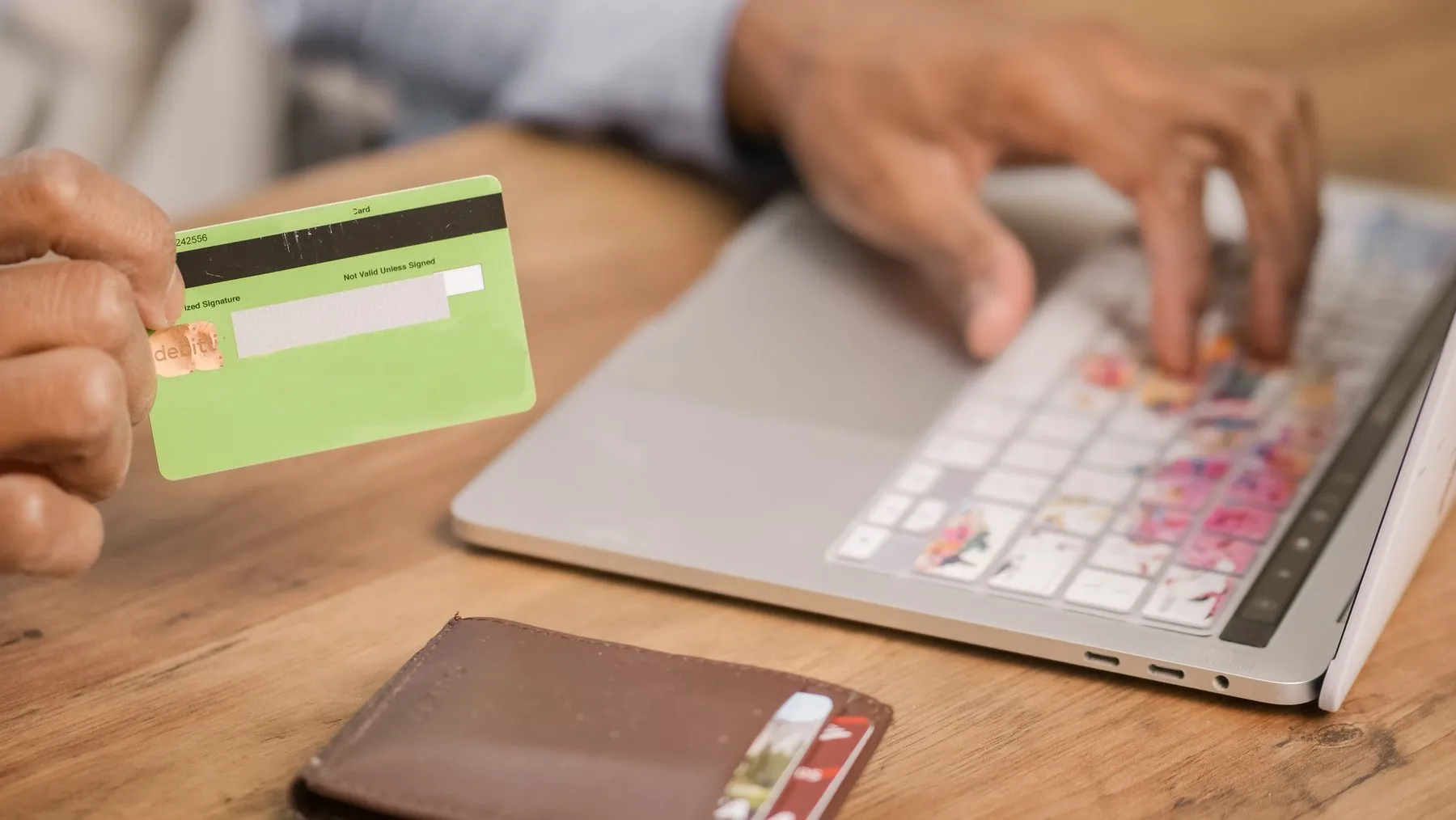 Hand holding a bank card while paying online on a laptop, illustrating GEL deposits to WhiteBIT