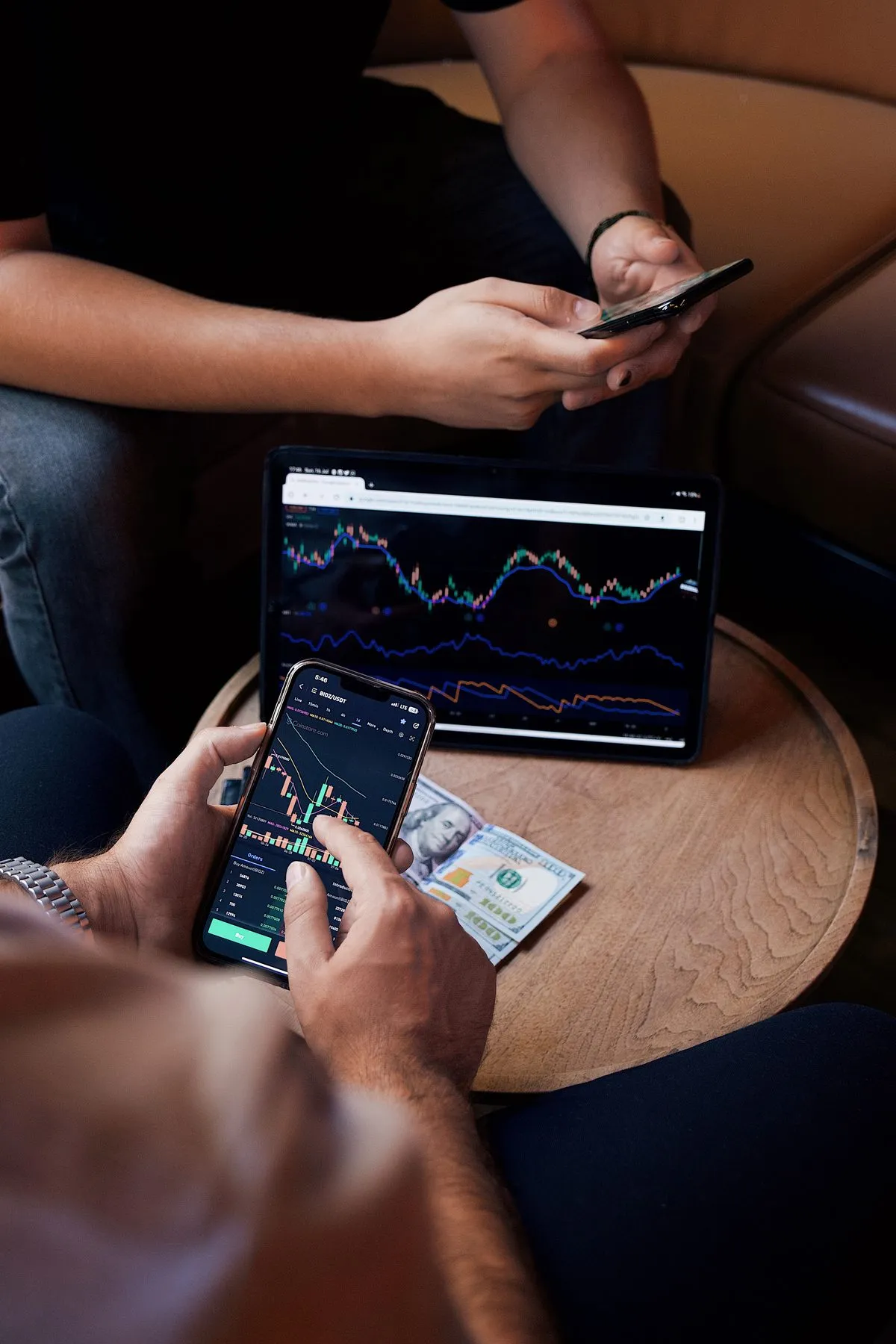 People checking trading apps on phones and a laptop